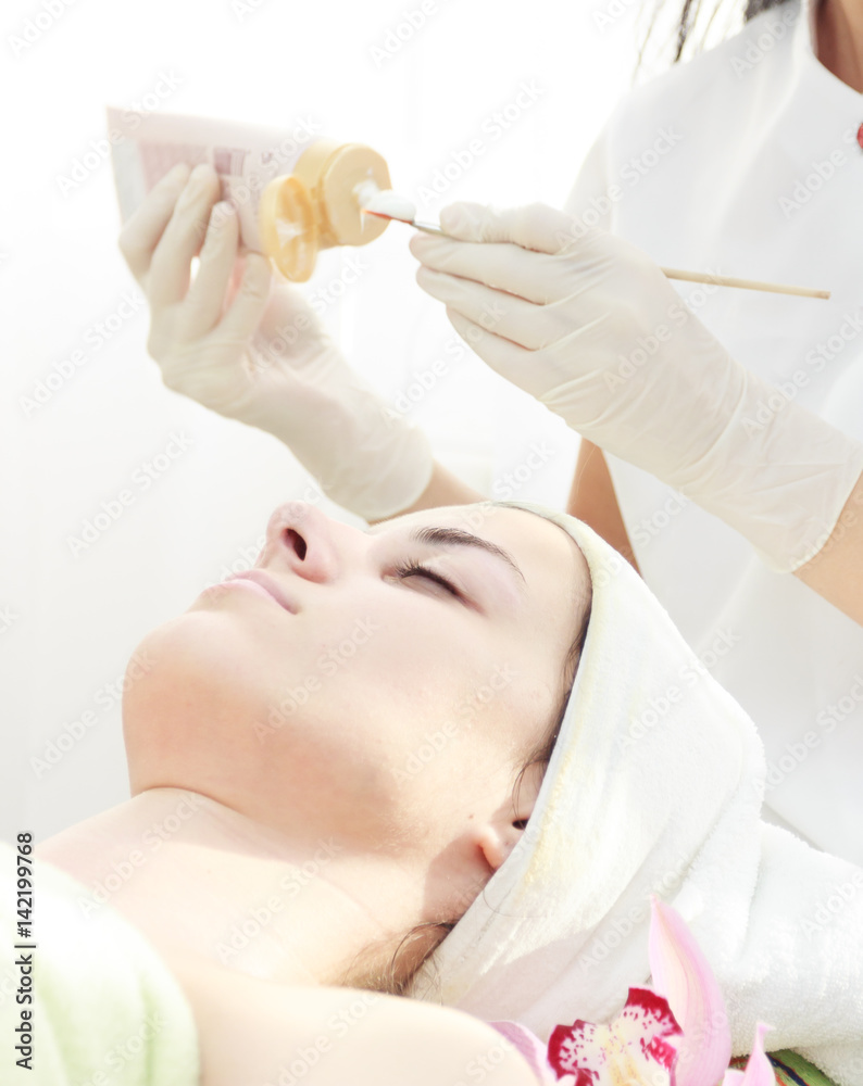 Naklejka premium Applying facial mask.Beautician applying facial mask to a beautiful young woman