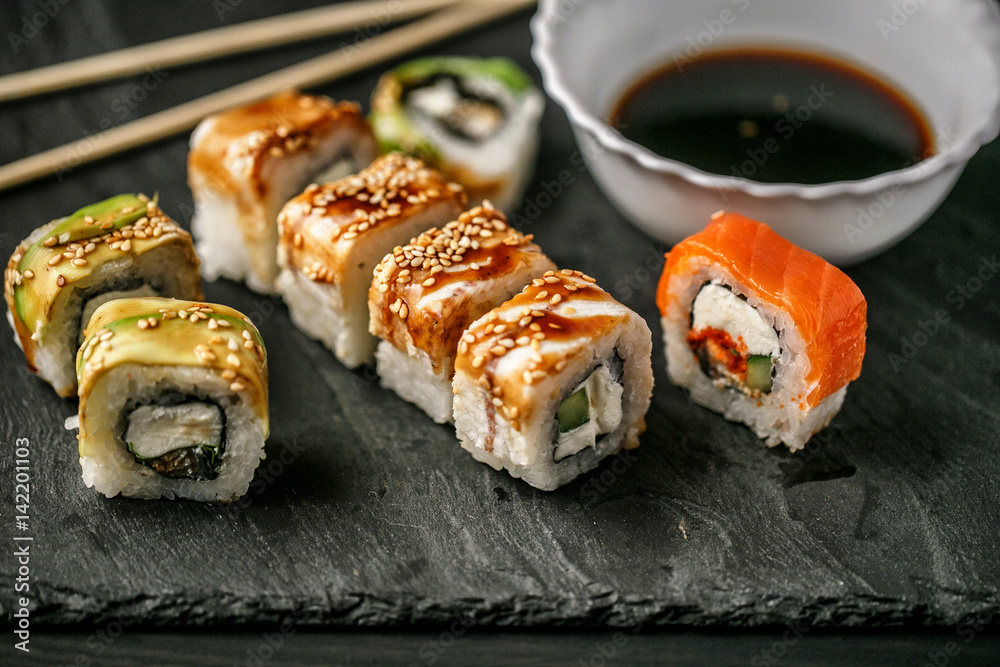 Delicious sushi with soy sauce on a slate board on a wooden background Delicious sushi with soy sauce on a slate board on a wooden background