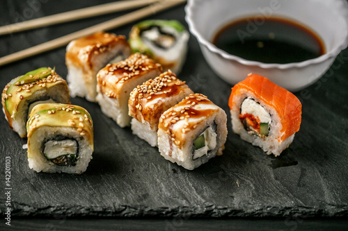 Delicious sushi with soy sauce on a slate board on a wooden background