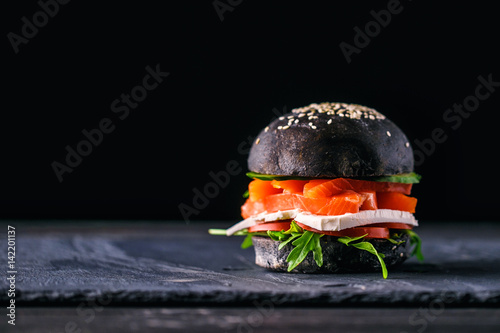 Delicious burgers of black dough with red fish on a beautiful slate board photo