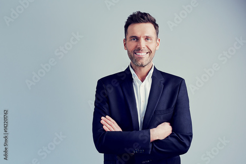 Fototapeta Happy businessman isolated - handsome man standing with crossed arms