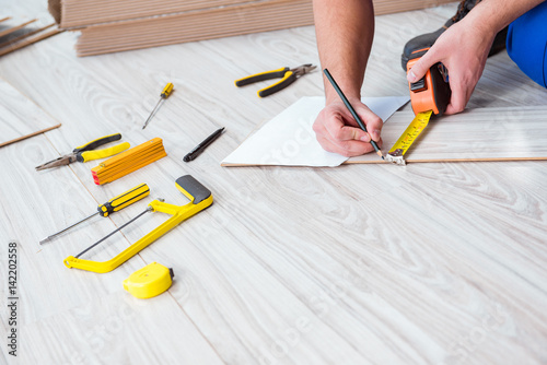 Repairman laying laminate flooring at home