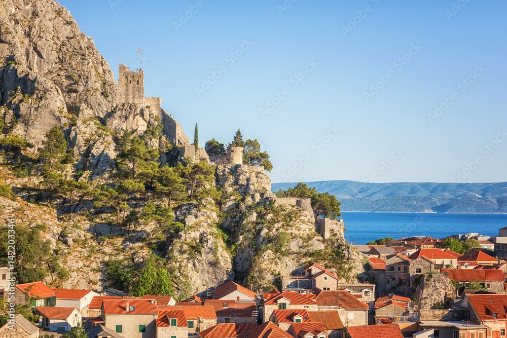 Old town of Omis with ancient fortress ruins on the rock and red roofs of the traditional mediterranean houses, Dalmatia, Croatia