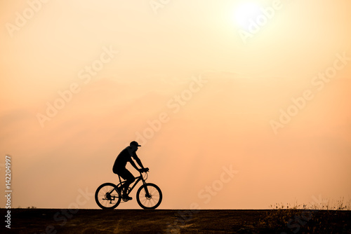 Silhouette of cyclist on sunset background