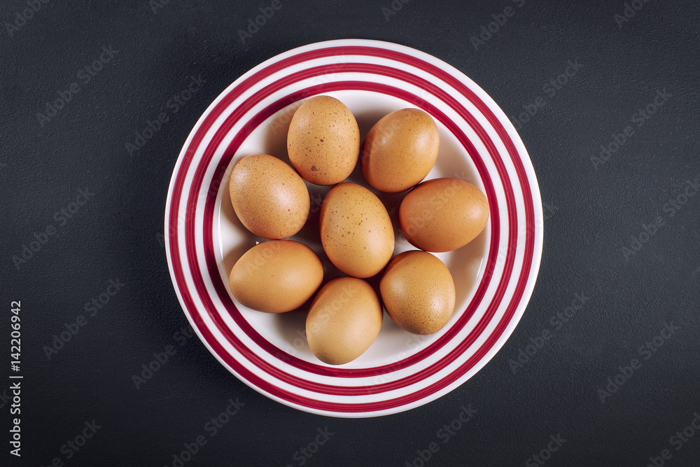 Fresh organic eggs on a stripped plate, view from top Fresh organic eggs on a stripped plate, view from top