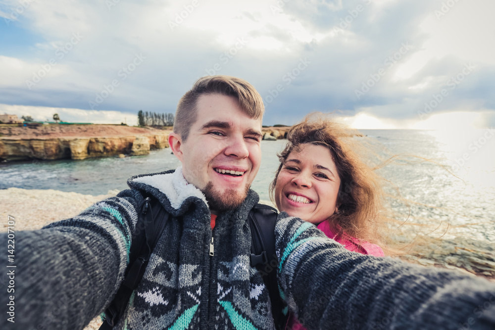 We love traveling. Adventure Selfie. Caucasian young couple taking selfie while they walking on mountains near the sea.
