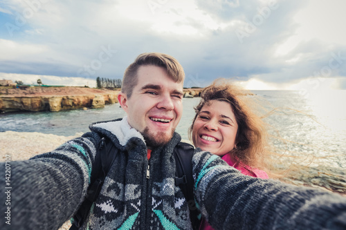 We love traveling. Adventure Selfie. Caucasian young couple taking selfie while they walking on mountains near the sea.