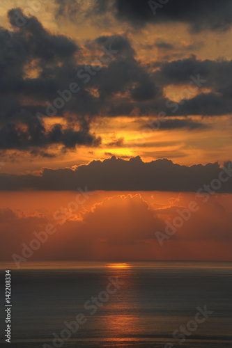 Breathtaking sunset over the Atlantic Ocean with thin clouds like molten lava  monochromatic vies with dark grey and golden yellow hues of the sunlight and clouds  in Tenerife  Canary Islands  Spain 