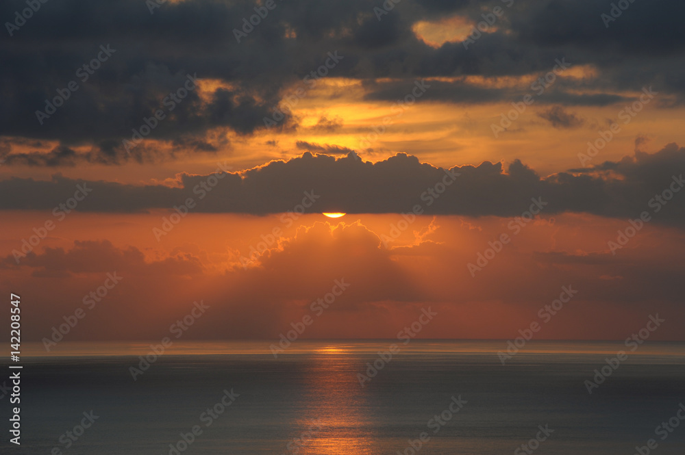 Atmospheric sunset over the Atlantic Ocean with thin clouds like molten lava, monochromatic vies with dark grey and golden yellow hues of the sunlight and clouds, in Tenerife, Canary Islands, Spain 