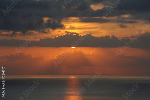 Atmospheric sunset over the Atlantic Ocean with thin clouds like molten lava, monochromatic vies with dark grey and golden yellow hues of the sunlight and clouds, in Tenerife, Canary Islands, Spain  © Ana