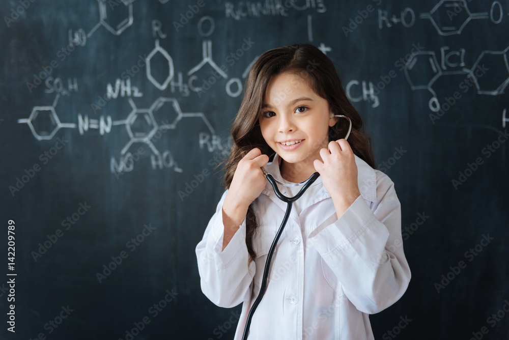 Cute young girl testing stethoscope at school