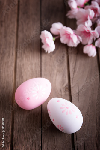 Branches of cherry tree with decorative easter eggs on wooden table