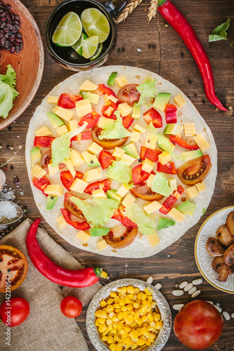 Tortilla with salad over it, surrounded by ingredients.