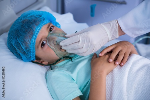 Doctor placing an oxygen mask on patient in ward