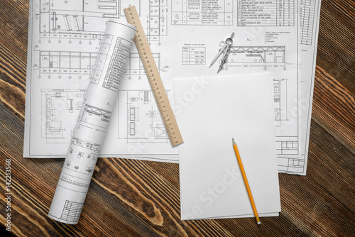 Blueprints on wooden table background with a pencil, a ruler and compasses lying beside. photo