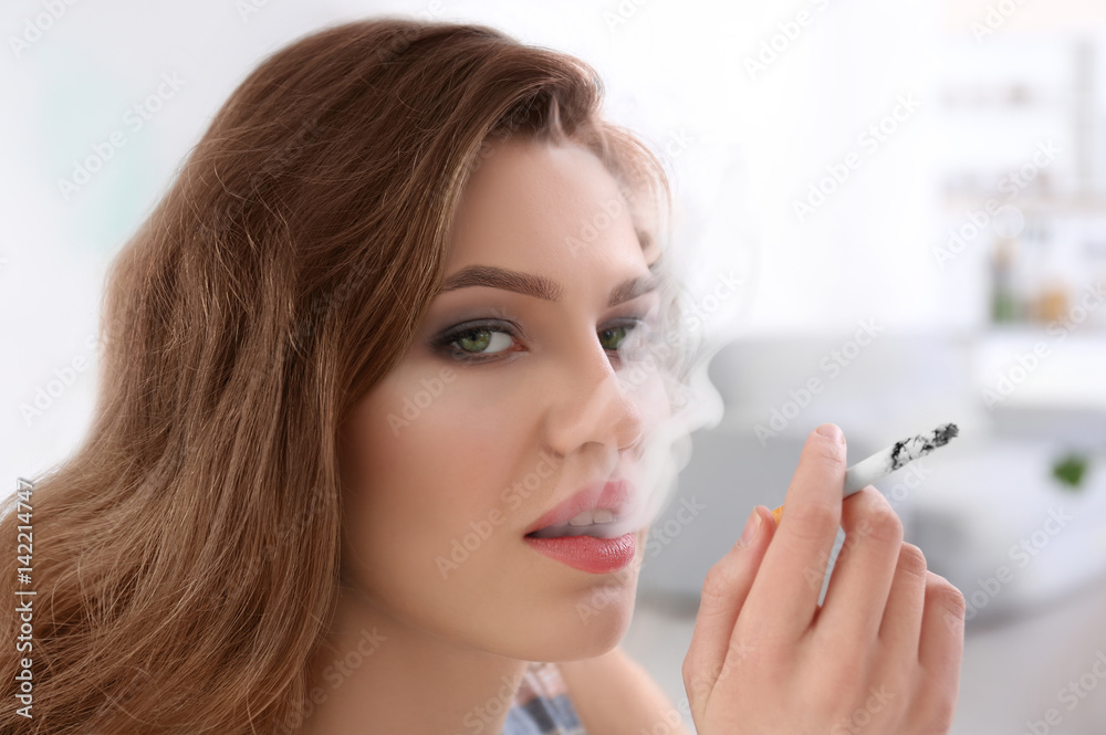 Portrait of young woman smoking in light room Portrait of young woman smoking in light room