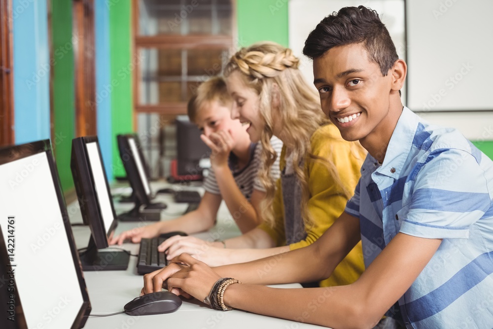 Smiling students studying in computer classroom