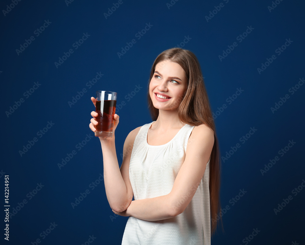 Beautiful young woman with glass of fresh juice on dark blue background Beautiful young woman with glass of fresh juice on dark blue background