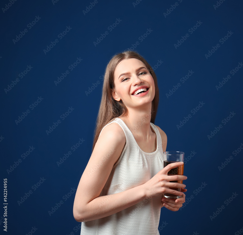 Beautiful young woman with glass of fresh juice on dark blue background Beautiful young woman with glass of fresh juice on dark blue background