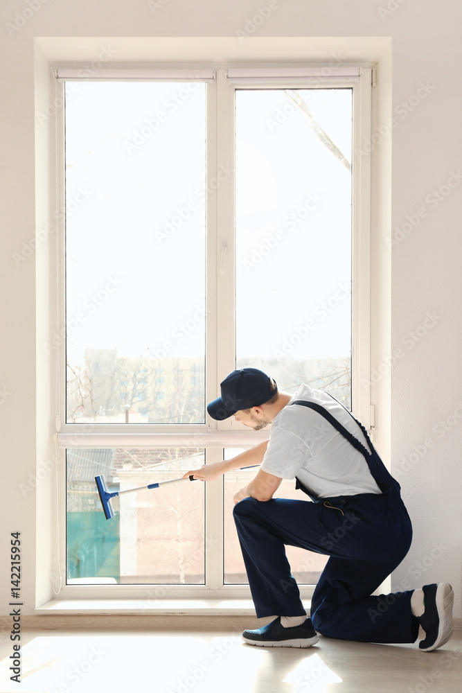 Young man washing window in office Young man washing window in office