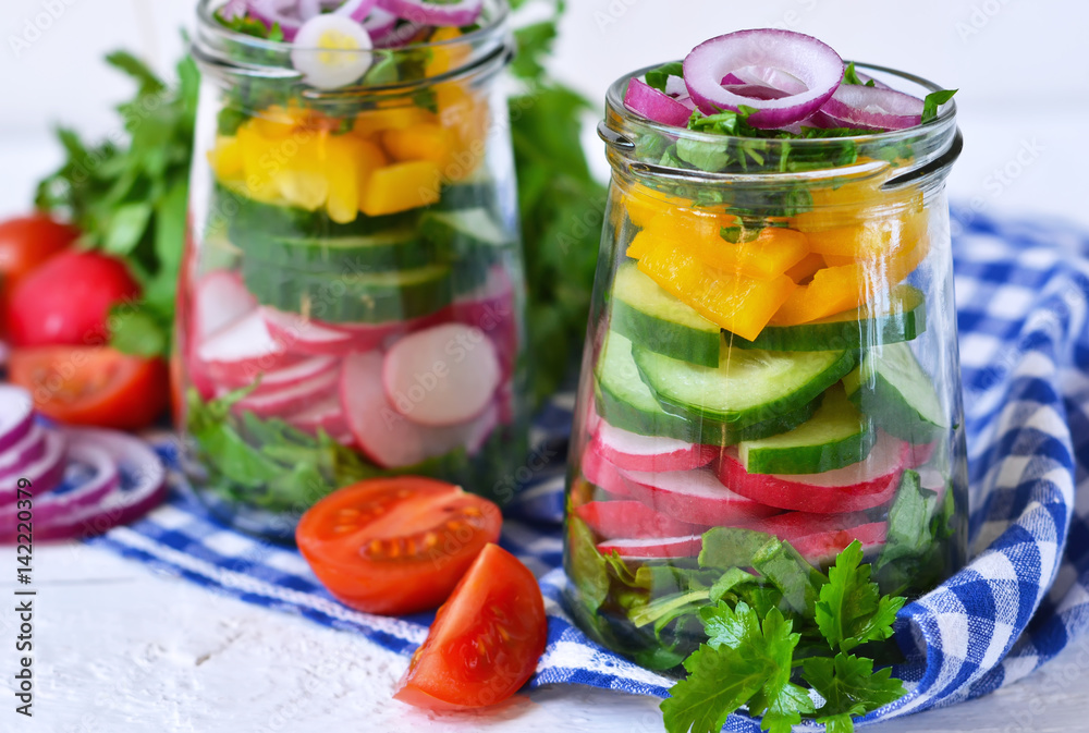 Vegetable salad with spinach and red onions in a glass jar on a white background Vegetable salad with spinach and red onions in a glass jar on a white background