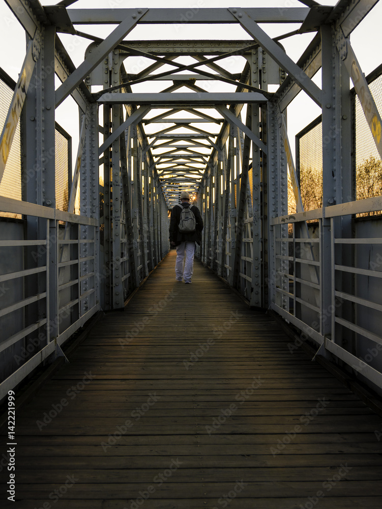 Symmetry view of footbridge over railway track with the man walking at sunset. Symmetry view of footbridge over railway track with the man walking at sunset.