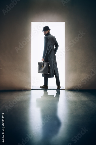 Quadro em tela Man silhouette standing in the light of opening door in dark room