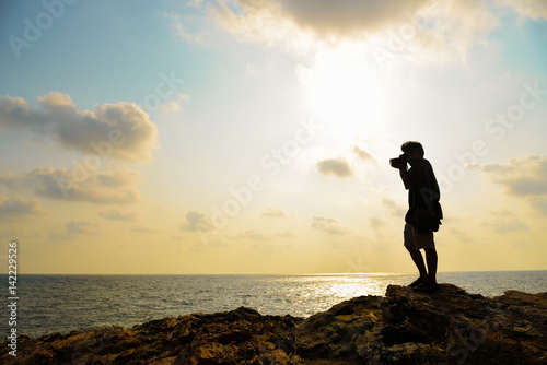 Silhouette of photographer taking photo on the top of mountaing photo