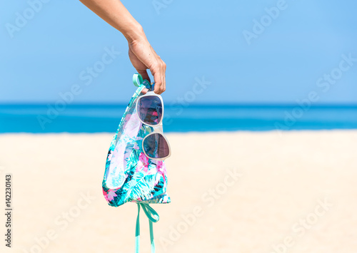 Woman hand holding biniki on beautiful beach. photo