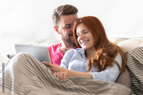 Young Couple Relaxing at Home and using tablet.