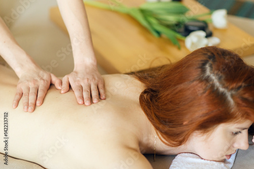 Close up of a masseuse's hands massaging female back.