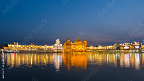 The Golden Temple at Amritsar, Punjab, India, the most sacred icon and worship place of Sikh religion. Illuminated in the night, reflected on lake. photo