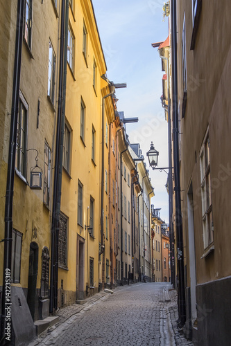 foot walk on narrow street of Stockholm in afternoon. High walls of close standing houses