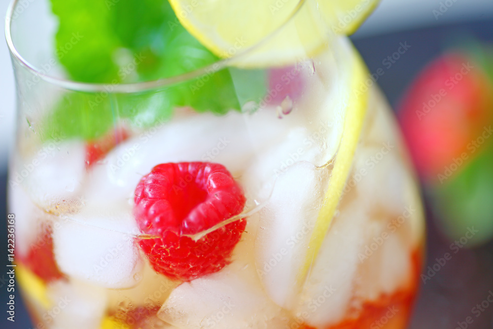 Closeup of cold drink with white wine, lemon, raspberries and mint Closeup of cold drink with white wine, lemon, raspberries and mint