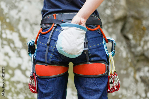 Female Climber with climbing equipment on the belt is ready to make her way up. Extreme sport