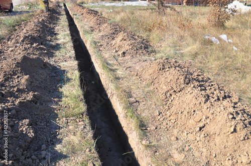 Digging a trench. Earthworks, digging trench. Long earthen trench dug to lay pipe or optical fiber.