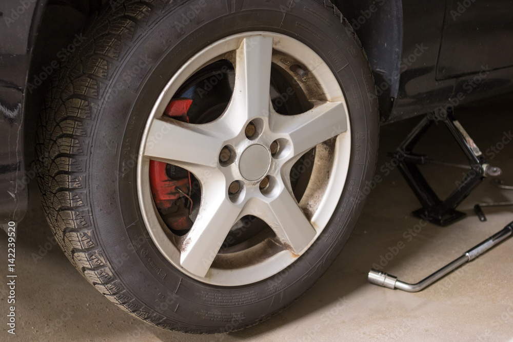 Reifenwechsel: aufgebocktes Auto und Radschlüssel
