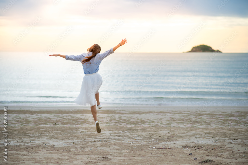 Young woman enjoys the beach with cheerful jump