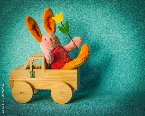 Easter bunny with a tulip traveling in a wooden car.