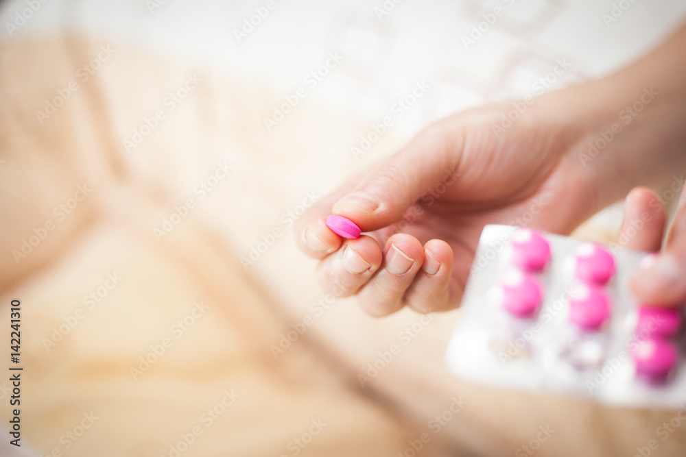 Young woman hands taking some pink pills, illness Young woman hands taking some pink pills, illness