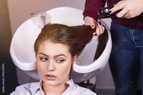 Portrait of women which washes her hair in a beauty salon. Hair stylist at work - hairdresser washing hair to the customer before doing hairstyle.