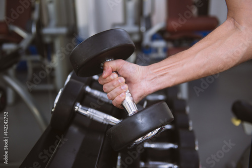 Hand of  man taking a dumbbell out of set of black weights photo