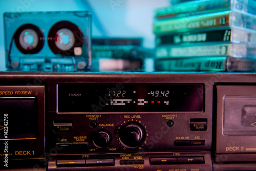 Close up CD audio cassette on the old fashioned cd player on the backgroud of stack of audio cassettes. Selective focus