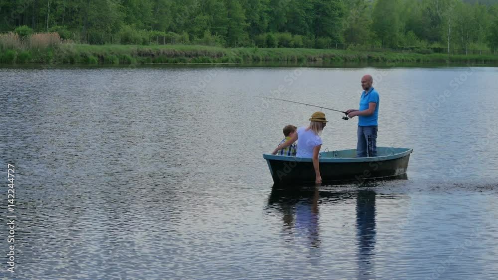 Mother, father and little son relaxing in boat on lake Mother, father and little son relaxing in boat on lake