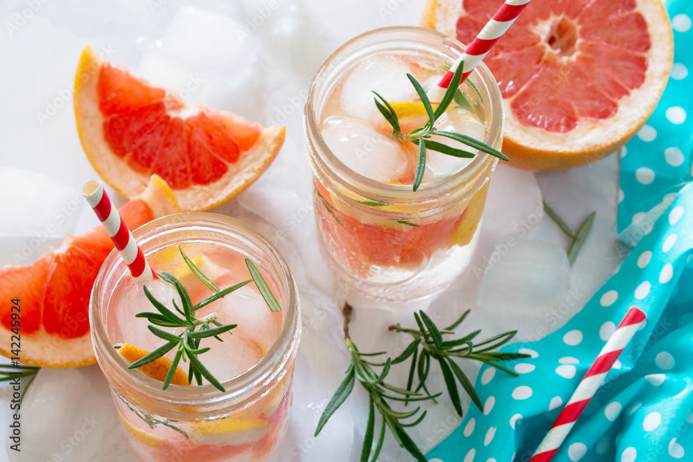 Refreshing summer drink with grapefruit and rosemary on a stone background. The concept of eating vegetarians, fresh vitamins, a homemade refreshing fruit drink. Refreshing summer drink with grapefruit and rosemary on a stone background. The concept of eating vegetarians, fresh vitamins, a homemade refreshing fruit drink.