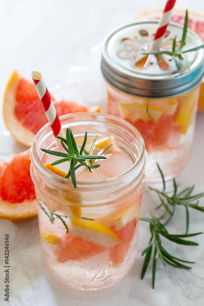 Refreshing summer drink with grapefruit and rosemary on a stone background. The concept of eating vegetarians, fresh vitamins, a homemade refreshing fruit drink. Refreshing summer drink with grapefruit and rosemary on a stone background. The concept of eating vegetarians, fresh vitamins, a homemade refreshing fruit drink.