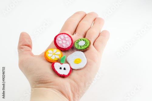 Handmade toy in the form of fruits and food made of felt stretched on a palm. Close-up of crafts with embroidery in hand