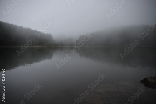 Mysterious dark lake in the morning mist photo