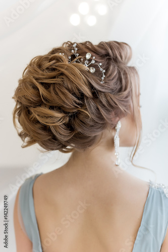 beautiful volume hairstyle for a bride in a gentle blue light dress with large earrings and adornment in hair