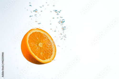 Orange in streams of water on a white background  studio light